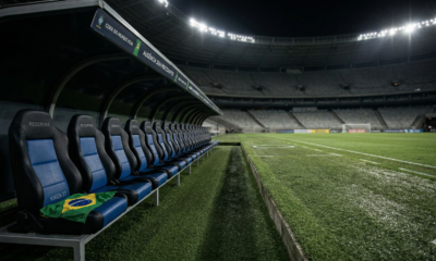Visão lateral de um banco de reservas vazio em um estádio de futebol profissional sob luzes noturnas