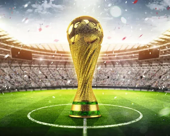 Imagem da Taça FIFA no centro de um gramado de um estádio de futebol lotado