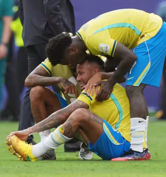 Atletas com a camisa amarela da Seleção Brasileira consolam Neymar sentado no gramado chorando e cabisbaixo após o apito final na Copa de 2026.